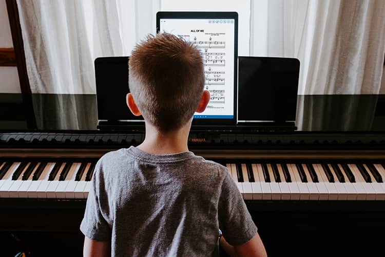 小男孩在用iPad上的音乐笔记应用弹钢琴